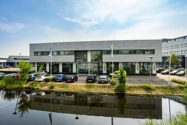 Kantoorgebouw aan de Rivium Boulevard met geparkeerde auto's en een waterpartij op de voorgrond.